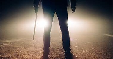 A person standing in the dark holding a stick