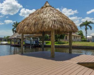 A boat dock with an umbrella and palm tree.