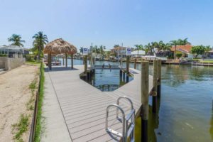 A dock with a boat ramp and palm trees.