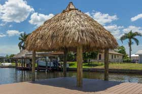 A boat dock with a thatched roof on the water.